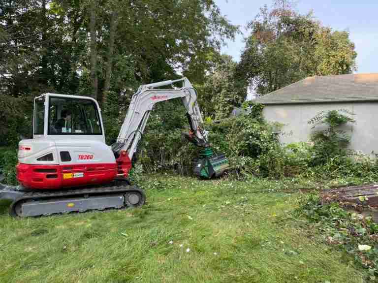 Brush mowing overgrown area near garage.