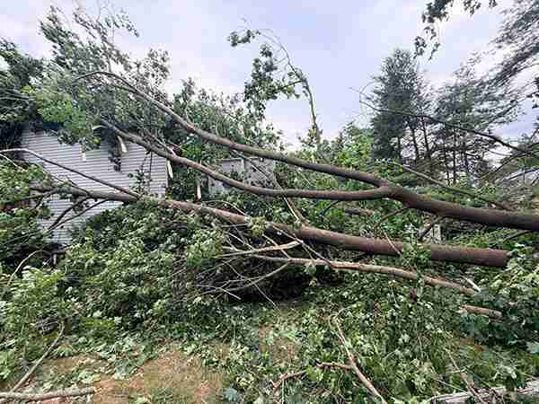 July 4th storm damage in CT showing trees having uprooted and fallen on a house.
