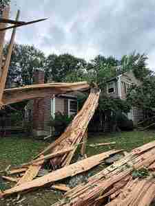 July 4th storm damage in Torrington showing a large splintered tree on a house.
